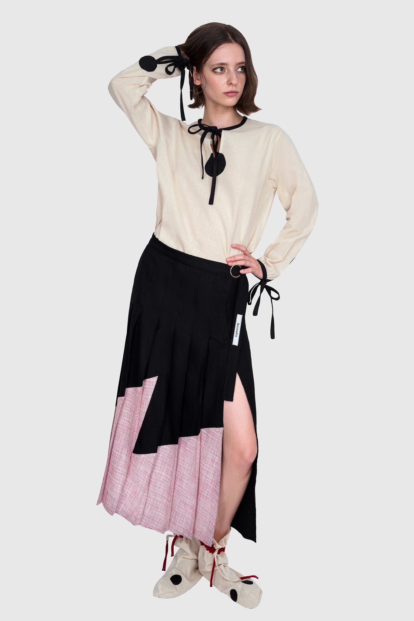 Pleated skirt and butter white blouse look, perfect holiday style for Swiss Alps, fresh and comfortable, slit opening on the side of the skirt, bow ties black accents on the blouse neckline and cuffs, cinema star fashion, black and pink and butter white