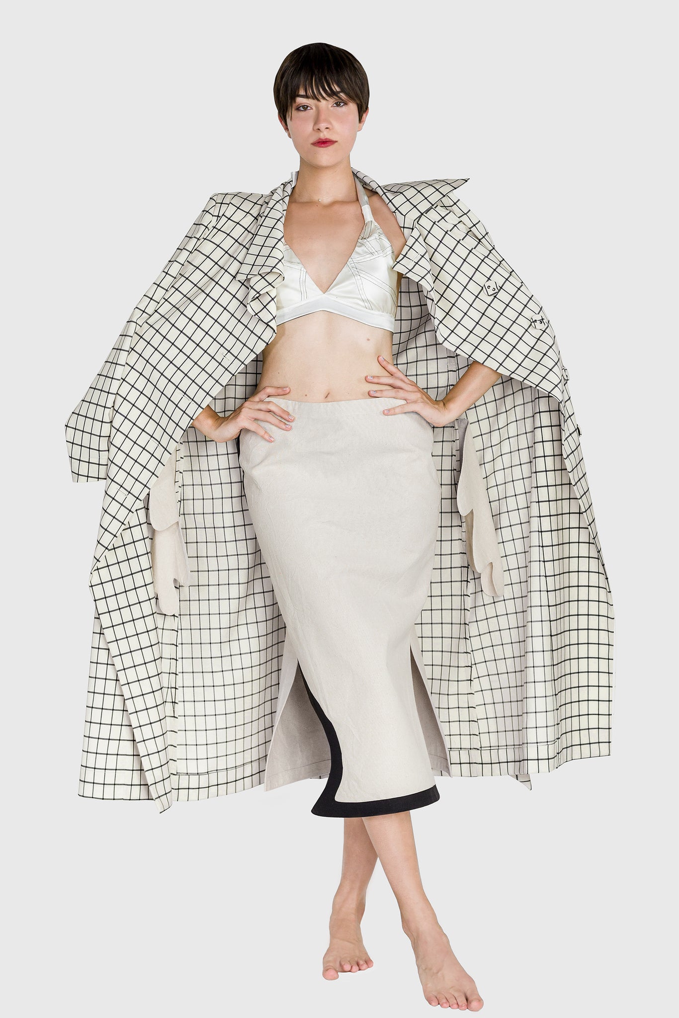 all white women's look, French style, grid pattern trench coat, white silk bra and white cotton low waist skirt, black lines contrast, curved side slit, heavy cotton, natural, sustainable, playful street style